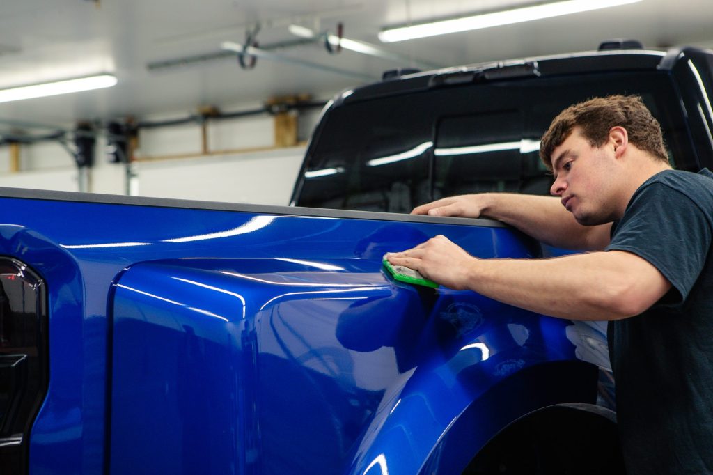 Krietz Customs technician wiping down the bed side of a blue Ford F-450 before ceramic coating.